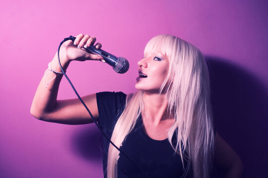 Side View Of Karaoke Singing Lady In Black T-shirt On Pink Background