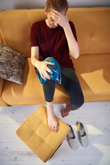 Woman with knee pain injury at home using ice gel pack.