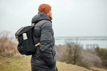Male hiker travelers with backpack walking along mountains against the river view