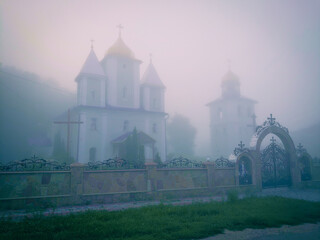 Church and bell tower in the fog. Christian temple in the mystical morning fog.