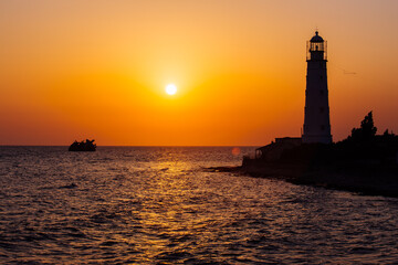 Lighthouse on the sea coast at sunset