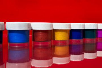 Colored acrylic paints in jars are in a row. 