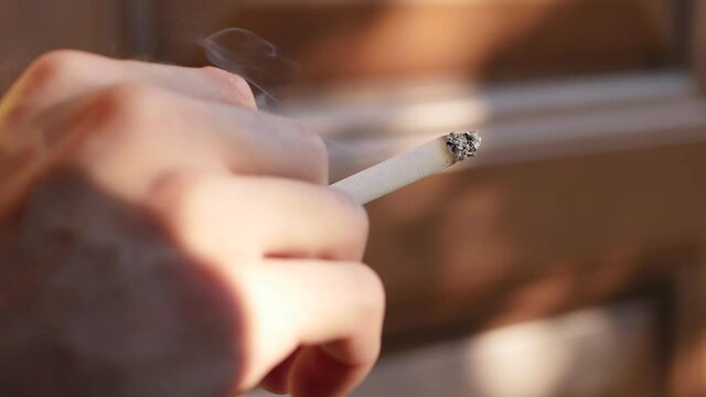 Close up male hand holding paper cigarette. Unhealthy lifestyle. Nicotine addiction. 4k video