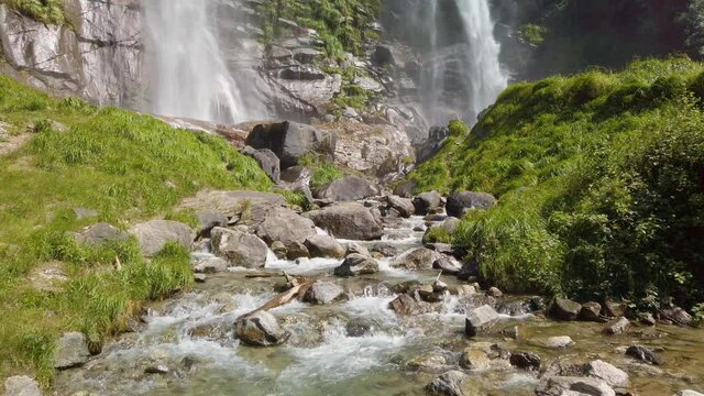 Water stream running from the beautiful Acquafraggia waterfall in Piuro, in the Bregaglia valley in Italy, before the ascent to the Maloja pass. It is a beautiful sunny summer day.
