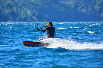 woman practicing extreme sport, kitesurfing at speed in the waters of a lake