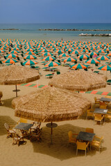 A beachfront during a sunny summer day with beach umbrellas and people swimming