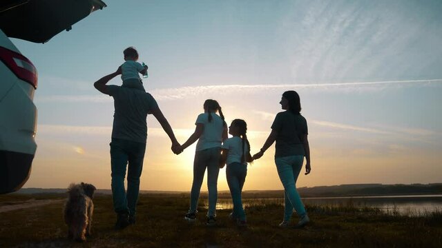 people in the park. happy family a silhouette walk at sunset. car travel kid dream concept. happy family parents and sun fun children walk silhouette next to car. family walk next to car
