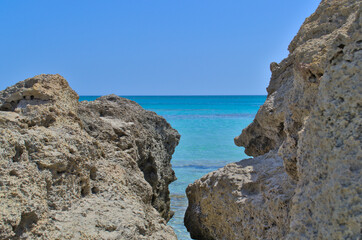 Fototapeta na wymiar View of the azure sea and blue sky through the stones.