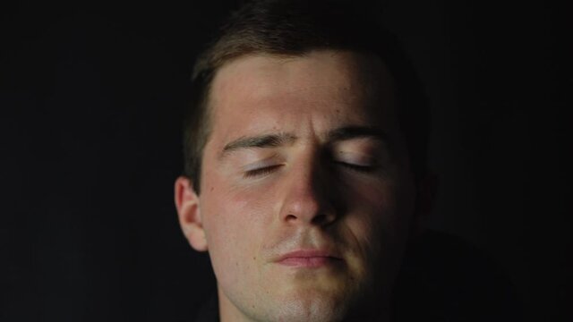 male gangster takes off his mask on a black background.