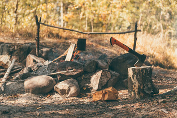 Autumn hiking. The axe in a stump and bowler on the campfire in background. Camping and hiking...