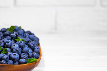 Blueberries With a Green Mint leaf in a Wooden Bowl on a white top view, Summer Freshly Berry, Copyspace