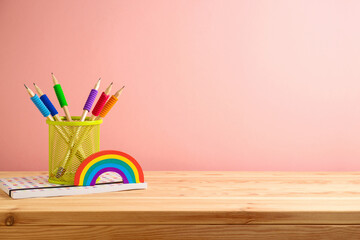 Back to school background with colorful pencils, book and rainbow on wooden table. Diversity and...