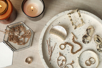Stylish golden bijouterie and candles on wooden table, flat lay