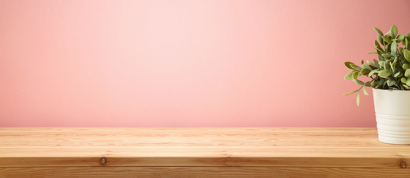Empty wooden table with home plant decor over pink wall background.  Interior mock up for design and product display.
