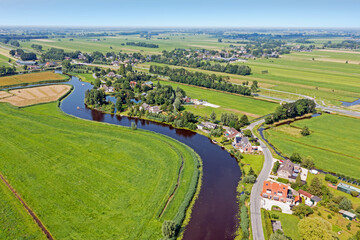 Fototapeta na wymiar Aerial from a traditional dutch landscape: A little river, houses and flat land in the Netherlands