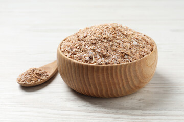 Bowl of wheat bran on white wooden table