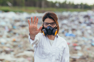 A woman in a protected respiratory suit at landfills, holding hands in front, trying to stop the...