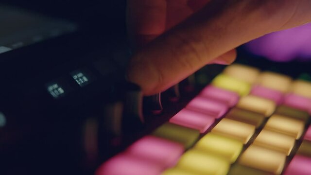Musician moving synth knob adjusting parameters
You can see the colored pads below that gently illuminate the hands of the musician who is in a dark environment