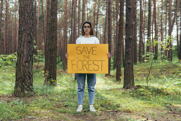 young woman volunteer in the woods pickets and holds a poster save the forest