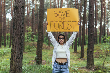 young woman volunteer in the woods pickets and holds a poster save the forest