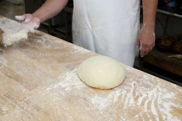 Baker kneading dough on wooden table