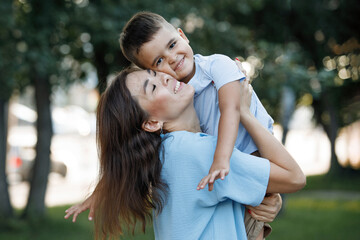 Fototapeta premium Mom with her son on hands in the summer park.