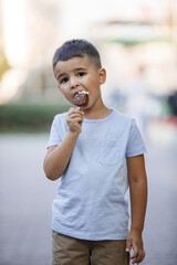 Boy eats ice cream in the summer park.