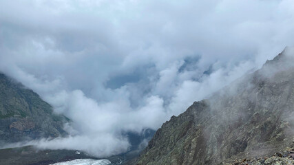Fog in the mountains. Majestic beautiful mountains, rocks, glacier. Climbing Kazbek from the north, from Russia.