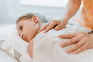Obraz na płótnie Canvas real doctor osteopath hands does physiological and emotional therapy for eight year old kid girl. pediatric osteopathy treatment session. alternative medicine. taking care of the child's health