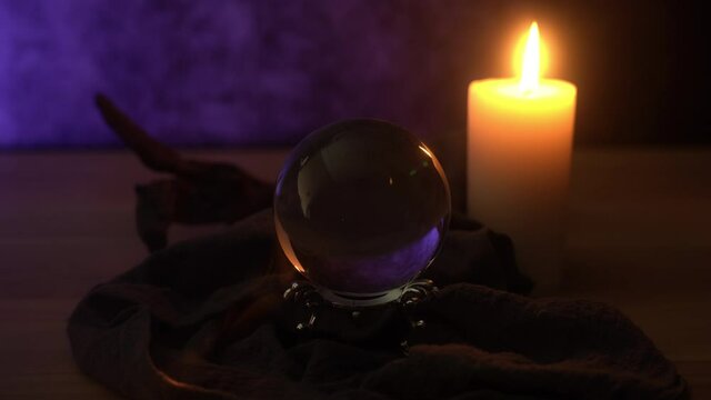 concept of mist fortune-telling wooden table and white candle with a crystal ball and tarot cards on dark background 4k footage	

