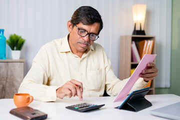 Businessman checking or verifying bills, expenses or taxes and calculating be seeing bills and...