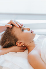 real doctor osteopath hands does physiological and emotional therapy for eight year old kid girl. pediatric osteopathy treatment session. alternative medicine. taking care of the child's health