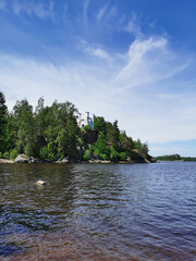 Fototapeta na wymiar View from the shore of the Ludwigsburg Chapel on Ludwigstein Island in the Monrepos Rock Nature Park of Vyborg against a beautiful blue sky with clouds.