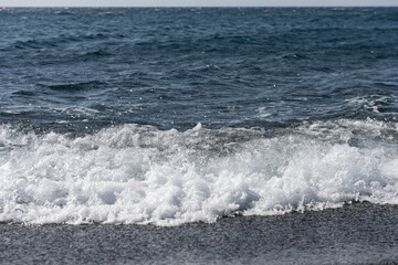 empty Black Sand beach in Santorini Greece early morning with small waves.