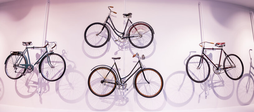 Old bicycles hang on a white wall as decorations