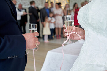 Hand of groom and bride holding glass of champaigne