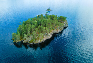 Small uninhabited island with lush green pine trees and sharp cliffs. Aerial drone view. © henjon