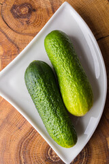 Two fresh green cucumbers on a white saucer. Healthy food concept.