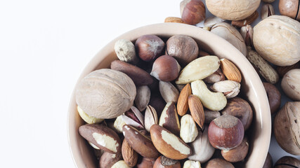 Nuts in ceramic dishes and nuts scattered on a white background top view. Assorted nuts of different types kopi space