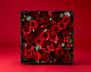 Close-up gift box full of flowers on red background