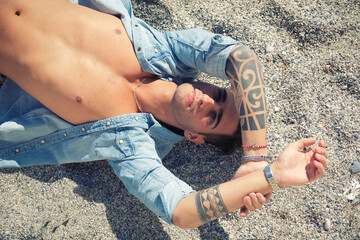 Handsome man laying on surfboard at beach