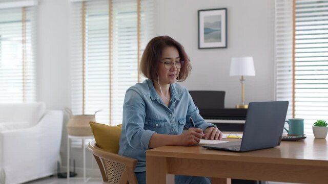 Asia adult people older lady remote distance work sit on desk at home smile happy watch SME owner live meeting class on MBA self tutor webcam webinar for reskill upskill job in web digital tablet.