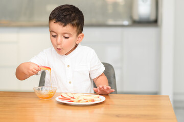Little Boy Eating Apple With Honey. Symbol of the Jewish New Year Rosh haShana.