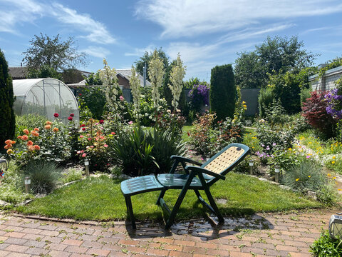 Backyard Of House With Flowers And Garden Recliner Chair