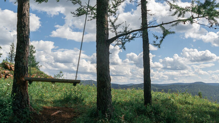 Swing on the top of the mountain against the backdrop of charming clouds.