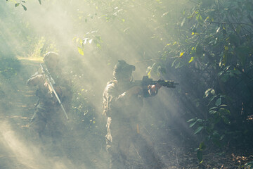 At a natural background, an army soldier in combat uniforms with an assault rifle or gun.