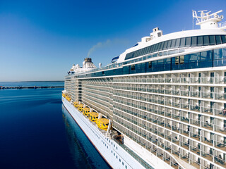 Starboard of a white cruise ship with balconies and lifeboats.