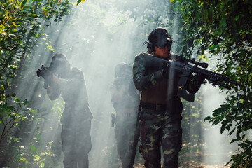 At a natural background, an army soldier in combat uniforms with an assault rifle or gun.