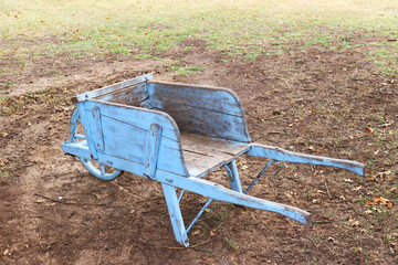 Old blue wheel barrel in a yard made of wood