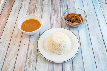 Dominican recipe with bowl of white rice, black bean stew and pork ribs cooked with time on wooden table